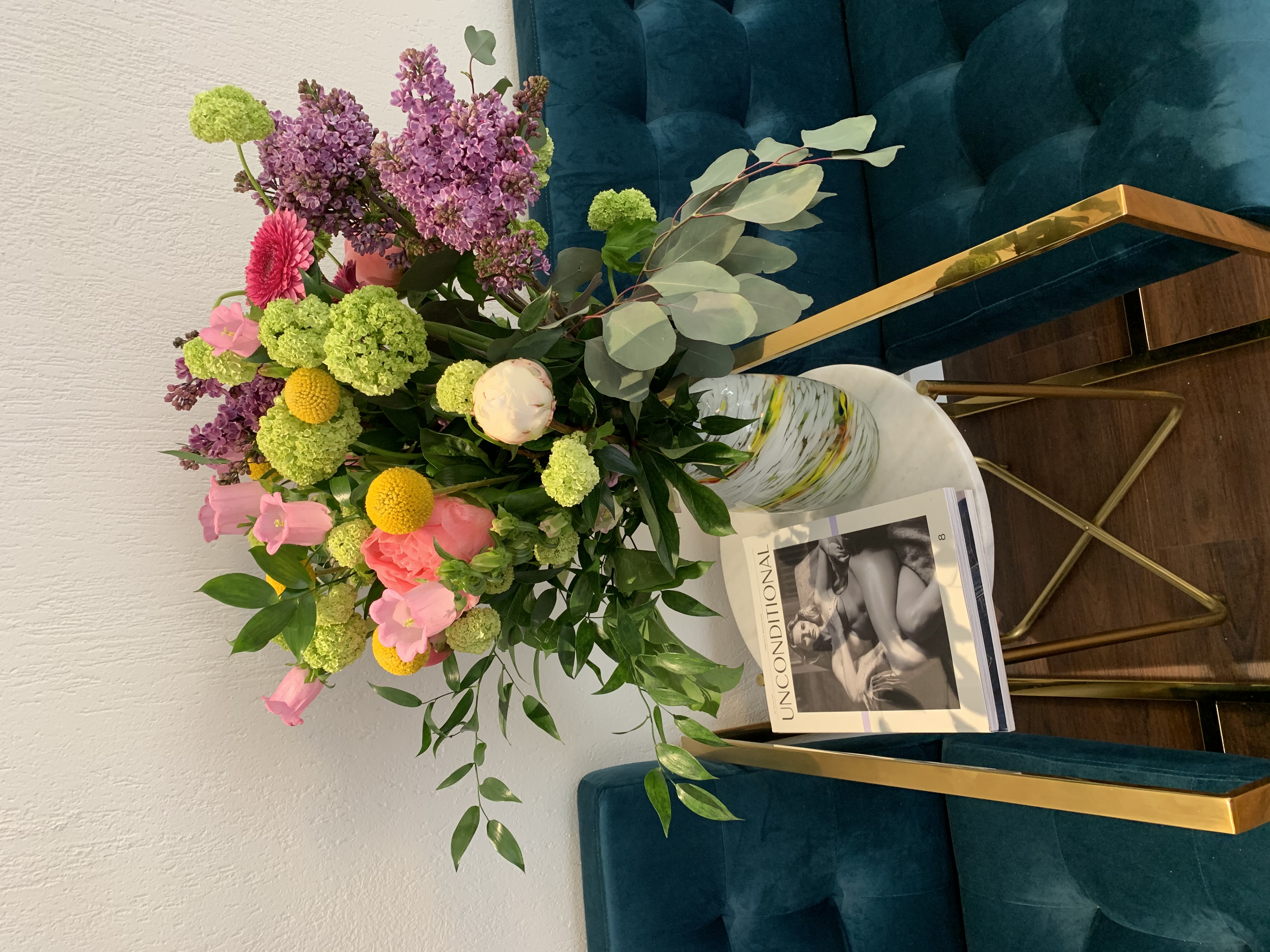 Fresh flowers on teal sofa — never without flower